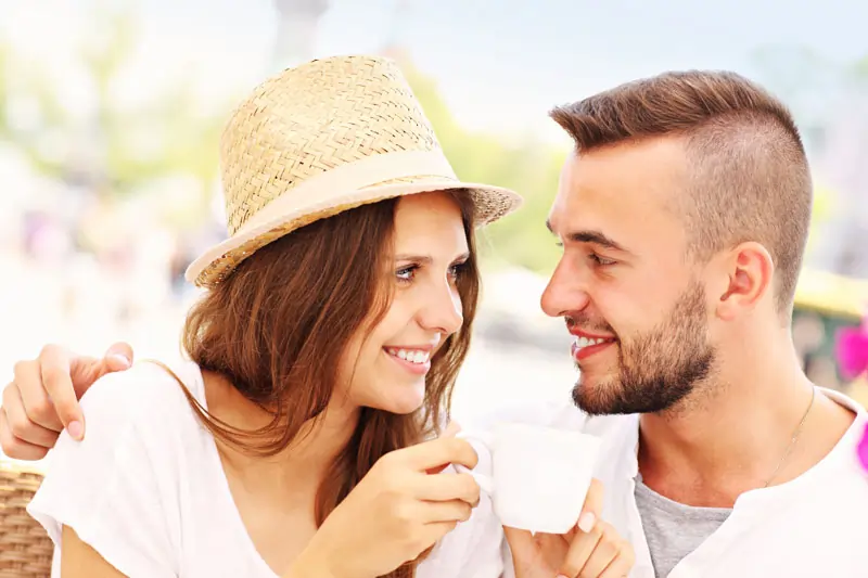 Ein verliebtes Paar, das sich beim gemeinsamen Kaffeetrinken tief in die Augen schaut und lächelt, um die Essenz der Liebe und Zuneigung darzustellen.