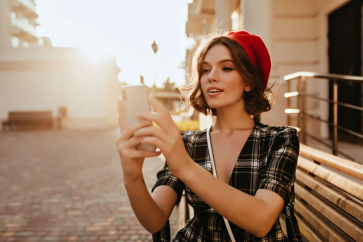 Eine selbstbewusste Frau, die ein Selfie macht, symbolisiert emotionale Unabhängigkeit und zeigt, wie wichtig es ist, den Ex loszulassen, damit er zurückkommt. Der friedliche Hintergrund vermittelt Selbstreflexion und persönliches Wachstum.