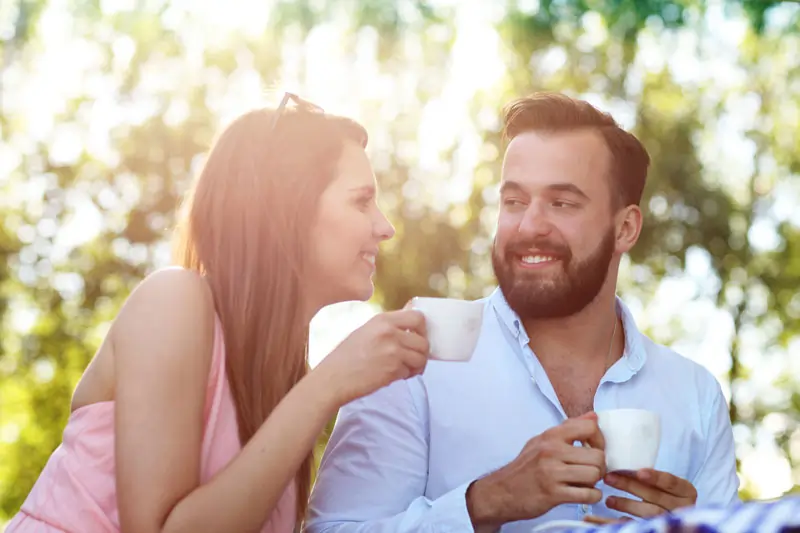 Ein Bild eines Paares, das sich in einem liebevollen Moment anschaut und zusammen Kaffee trinkt, um die persönlichen Liebesnachrichten zu symbolisieren.