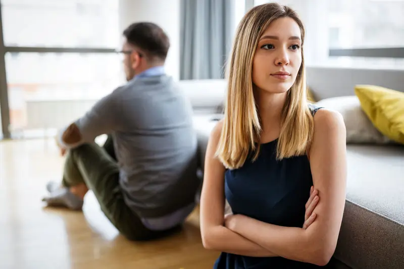Ein Paar sitzt getrennt und nachdenklich im Wohnzimmer, zeigt die Ursachen und Gründe, warum die Liebe weg ist.
